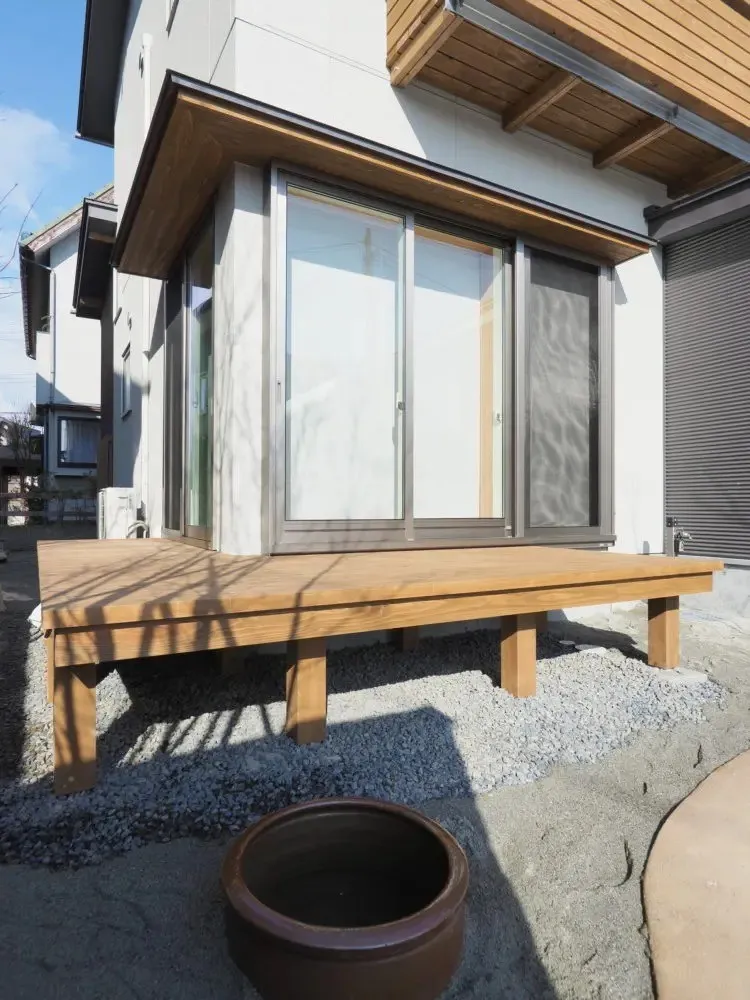 ウッドデッキはアプローチと一体にも見える。<br>埋め込んだカメにはこれから水草やメダカなどを入れ、暮らしを愉しむ。